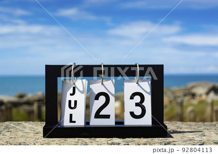 Jul 23 calendar date text on wooden frame with blurred background of ocean. 92804113