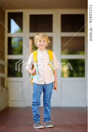 Little student with a backpack at the door of school building. Back to school concept. 92805151