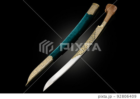 souvenir collectible silver gold dagger cutlass with scabbard, with metal engraving, on black background. Luxury weapons with traditional patterns in medieval vintage style. 92806409