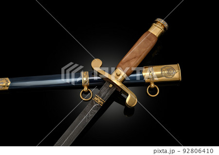 souvenir collectible silver gold dagger cutlass with scabbard, with metal engraving, on black background. Luxury weapons with traditional patterns in medieval vintage style. 92806410