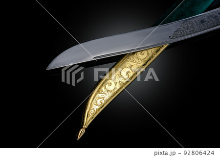 souvenir collectible silver gold dagger cutlass with scabbard, with metal engraving, on black background. Luxury weapons with traditional patterns in medieval vintage style. souvenir collectible silver gold dagger cutlass with scabbard, with metal engraving, on black background. Luxury weapons with traditional patterns in medieval vintage style. 92806424
