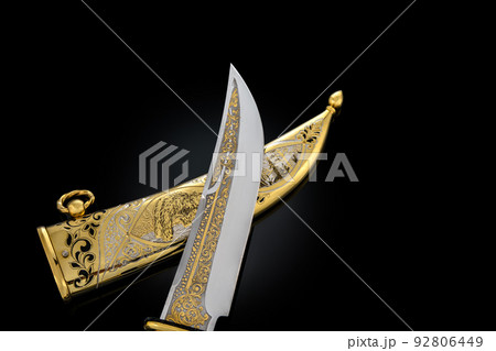 souvenir collectible silver gold dagger cutlass with scabbard, with metal engraving, on black background. Luxury weapons with traditional patterns in medieval vintage style. souvenir collectible silver gold dagger cutlass with scabbard, with metal engraving, on black background. Luxury weapons with traditional patterns in medieval vintage style. 92806449