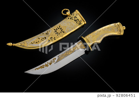 souvenir collectible silver gold dagger cutlass with scabbard, with metal engraving, on black background. Luxury weapons with traditional patterns in medieval vintage style. souvenir collectible silver gold dagger cutlass with scabbard, with metal engraving, on black background. Luxury weapons with traditional patterns in medieval vintage style. 92806451
