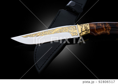 souvenir collectible silver gold dagger cutlass with scabbard, with metal engraving, on black background. Luxury weapons with traditional patterns in medieval vintage style. 92806517