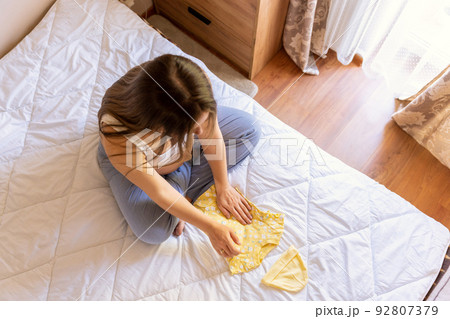 Pregnant woman baby clothes. Beautiful pregnancy mother with yellow baby clothes. Pregnant woman hugging belly and packing maternity hospital bag. Concept maternity, pregnancy, childbirth. Pregnant woman baby clothes. Beautiful pregnancy mother with yellow baby clothes. Pregnant woman hugging belly and packing maternity hospital bag. Concept maternity, pregnancy, childbirth. 92807379