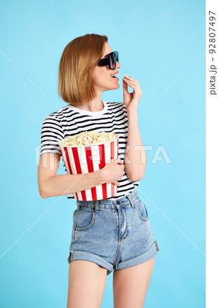 woman watching movie film, holding bucket of popcorn 92807497