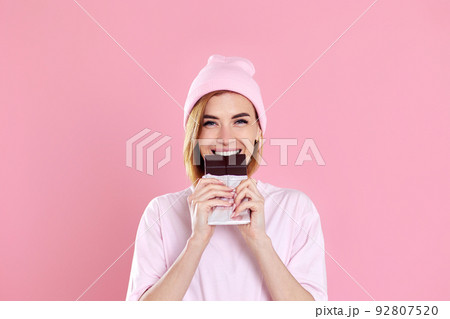 young happy woman in casual t-shirt biting sweet chocolate bar 92807520