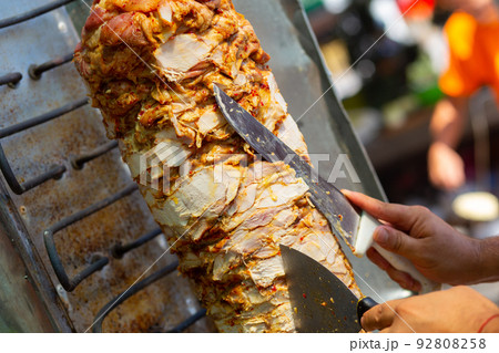 Chef cutting with doner knife Traditional Turkish Doner Kebab meat. Chef cutting with doner knife Traditional Turkish Doner Kebab meat. 92808258