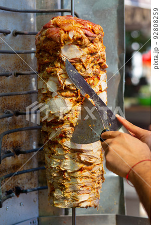 Chef cutting with doner knife Traditional Turkish Doner Kebab meat. 92808259