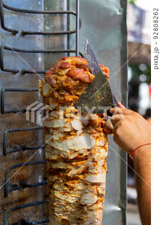Chef cutting with doner knife Traditional Turkish Doner Kebab meat. 92808262