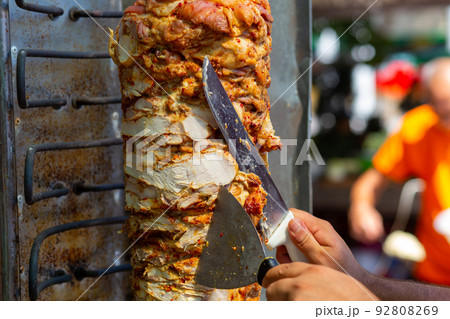 Chef cutting with doner knife Traditional Turkish Doner Kebab meat. Chef cutting with doner knife Traditional Turkish Doner Kebab meat. 92808269