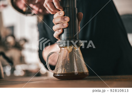 Professional Barista press to device and coffee drops pours trought aeropress to pot Professional Barista press to device and coffee drops pours trought aeropress to pot 92810613