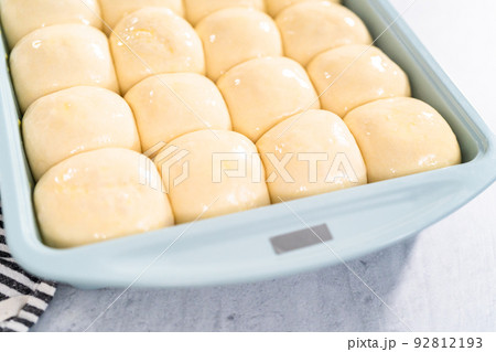 Brushing dinner rolls with mixture of egg and milk before baking in the baking pan. Brushing dinner rolls with mixture of egg and milk before baking in the baking pan. 92812193