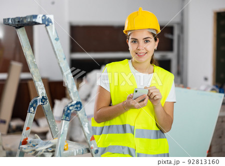 Woman builder writes a message or makes an order for building materials on phone 92813160