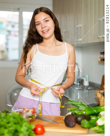 Young pretty girl measuring her waist with measuring tape Young pretty girl measuring her waist with measuring tape 92813214
