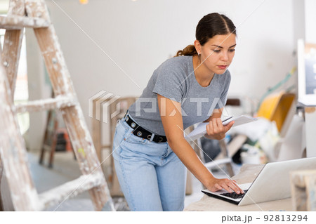 Owner of the cottage checks the completion of repair work using laptop 92813294
