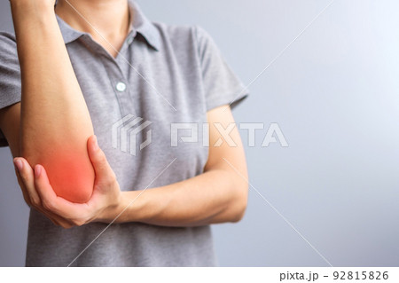 adult female with her muscle pain on gray background. Woman having elbow ache due to lateral epicondylitis or tennis elbow. injuries and medical concept 92815826