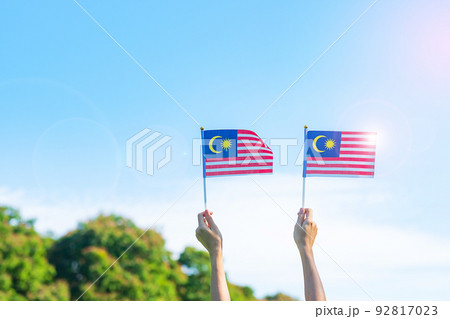 hand holding Malaysia flag on blue sky background. September Malaysia national day and August Independence day hand holding Malaysia flag on blue sky background. September Malaysia national day and August Independence day 92817023