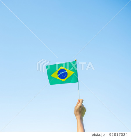 hand holding Brazil flag on blue sky background. September Independence day and Happy celebration concepts hand holding Brazil flag on blue sky background. September Independence day and Happy celebration concepts 92817024