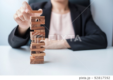 Businesswoman hand placing or pulling wooden block on the tower. Business planning, Risk Management, Solution and strategy Concepts 92817592