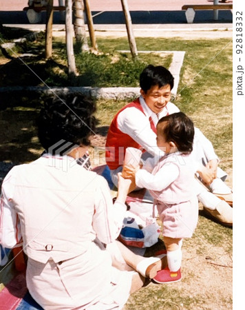 昭和50年代　公園でランチを楽しむ両親と1歳の女の子 92818332