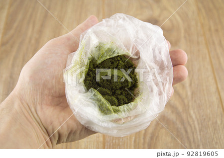 carcinogenic chewing tobacco powder (nas, nasvay, dip, snus) from Tajikistan, in a  bag in the man's hand, side view 92819605