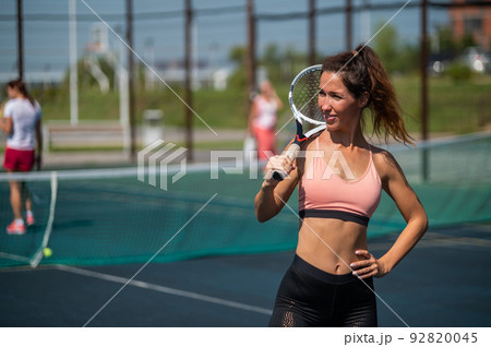 Beautiful European woman posing on a tennis court and holding a rocket Beautiful European woman posing on a tennis court and holding a rocket 92820045