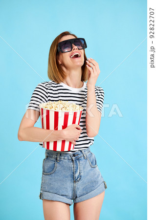 woman watching movie film, holding bucket of popcorn 92822707