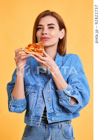 young woman with pizza slice on yellow background. young woman with pizza slice on yellow background. 92822737