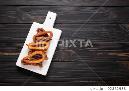 Homemade churros on a wooden black background. 92822988
