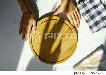 Man hand holding empty round wooden pizza board in hand, white background. Mockup Man hand holding empty round wooden pizza board in hand, white background. Mockup 92825720