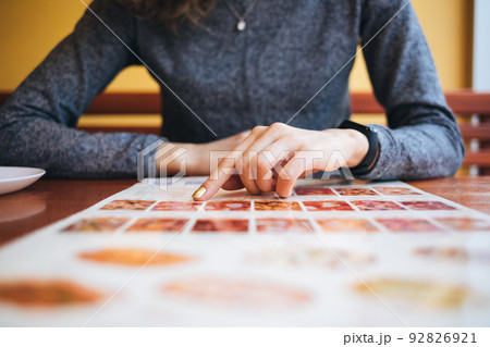 Close-up of unrecognizable young woman reading menu 92826921