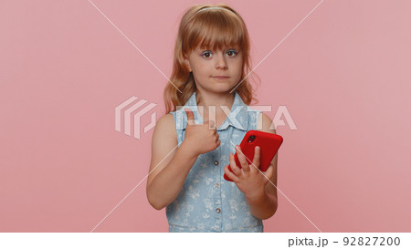 Child girl kid use smartphone social media online, watching movie, show thumbs up like, feedback 92827200