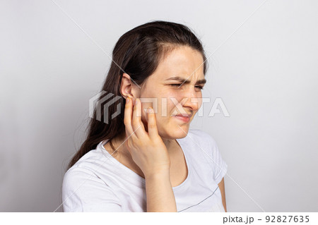 The woman has a sore ear - infection, inflammation from infection and otitis. Perforation ruptured the eardrum. Arthritis of the temporal lower jaw joint, osteoarthritis and pain in the jaw 92827635