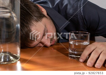 A man in alcoholic intoxication holds a glass of alcohol. Alcoholism, addiction, delirium A man in alcoholic intoxication holds a glass of alcohol. Alcoholism, addiction, delirium 92827653