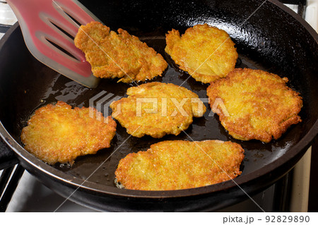 The cooking process in a pan of potato pancakes. Frying potato pancakes in vegetable oil. The cooking process in a pan of potato pancakes. Frying potato pancakes in vegetable oil. 92829890
