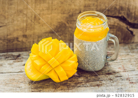 Chia seed pudding with almond milk and fresh mango topping on a wooden table Chia seed pudding with almond milk and fresh mango topping on a wooden table 92832915