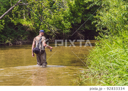 Man fishing on a mountain river with a ultralight spinning using fishing wobblers. He got his hook hooked for something Man fishing on a mountain river with a ultralight spinning using fishing wobblers. He got his hook hooked for something 92833334