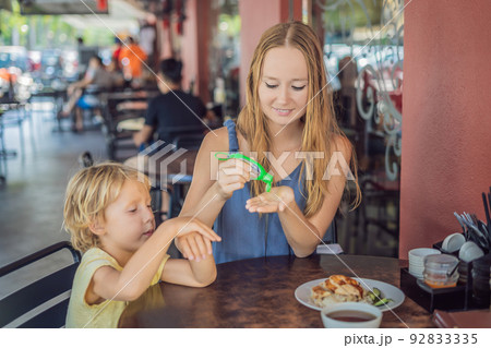 Mother and son using wash hand sanitizer gel in a cafe before eating Mother and son using wash hand sanitizer gel in a cafe before eating 92833335