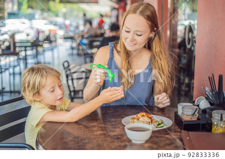 Mother and son using wash hand sanitizer gel in a cafe before eating 92833336