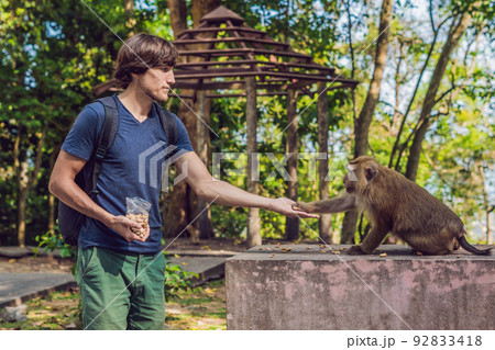 The man feeds the monkey whith nuts 92833418