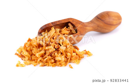 Roasted onions in wooden scoop, isolated on white background. Crispy fried onions. 92833441