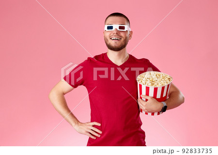Young caucasian man in 3d glasses eating popcorn Young caucasian man in 3d glasses eating popcorn 92833735