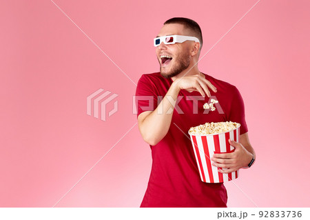 Young caucasian man in 3d glasses eating popcorn Young caucasian man in 3d glasses eating popcorn 92833736