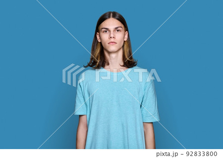 Portrait of serious teenage guy looking at camera on blue background 92833800