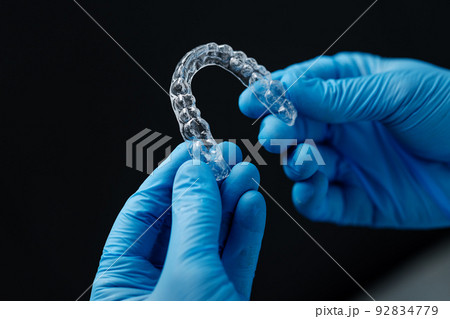 Invisible orthodontics cosmetic aligners in hands of doctor 92834779