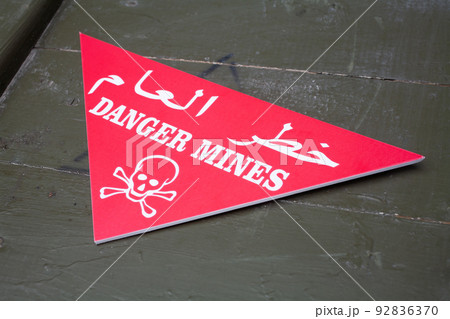 Arabic/English minefield warning red sign - Danger Mines. White skull-and-crossbones on a red. Arabic/English minefield warning red sign - Danger Mines. White skull-and-crossbones on a red. 92836370