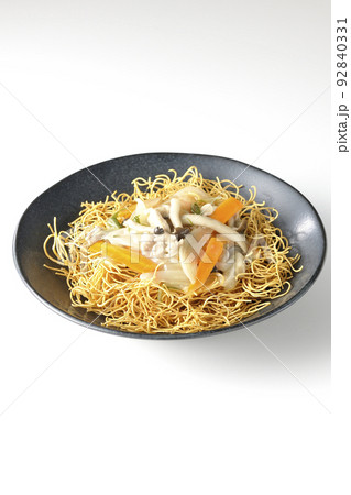 しめじや人参、玉葱などが入っている餡がかかった皿うどんを白背景で撮影 92840331