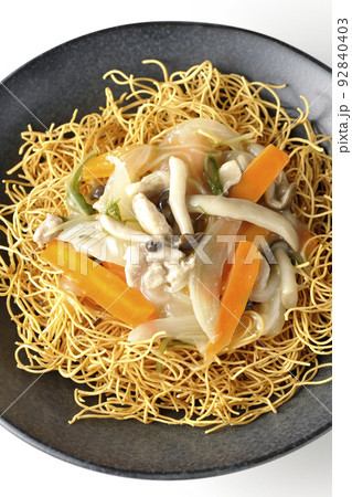 しめじや人参、玉葱などが入っている餡がかかった皿うどんを白背景で俯瞰撮影 92840403