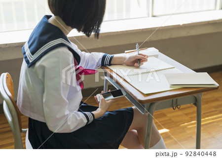 授業中に携帯電話を見る女子高生 92840448